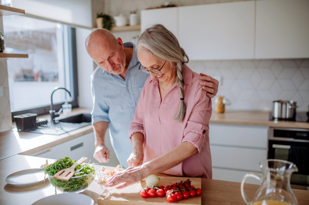 Happy senior couple cooking together at home.